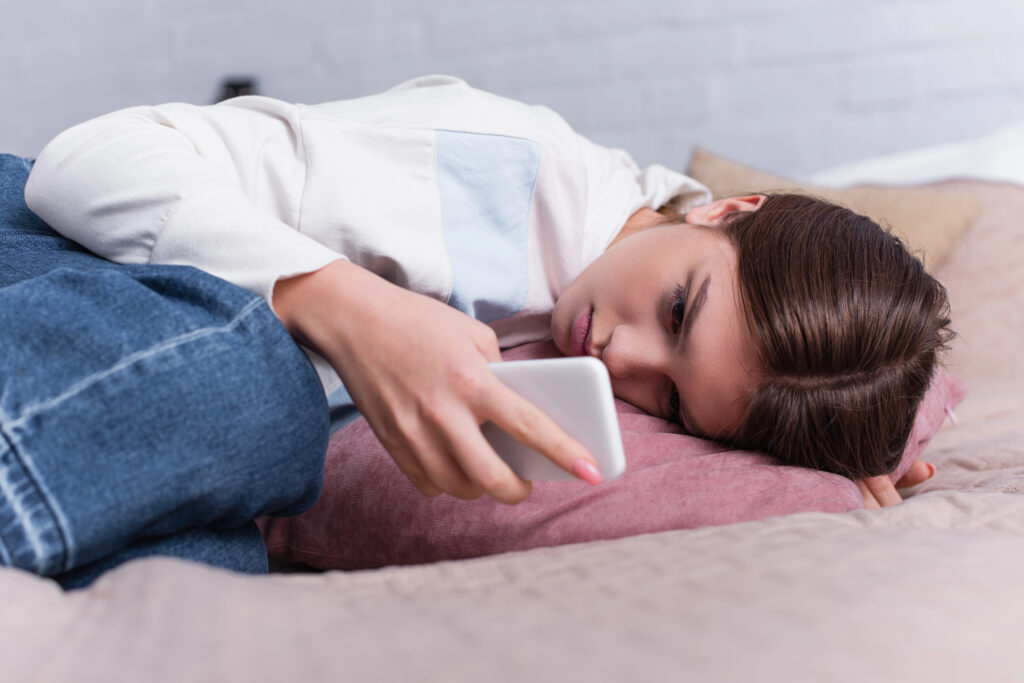 Teen looks at her phone while depressed