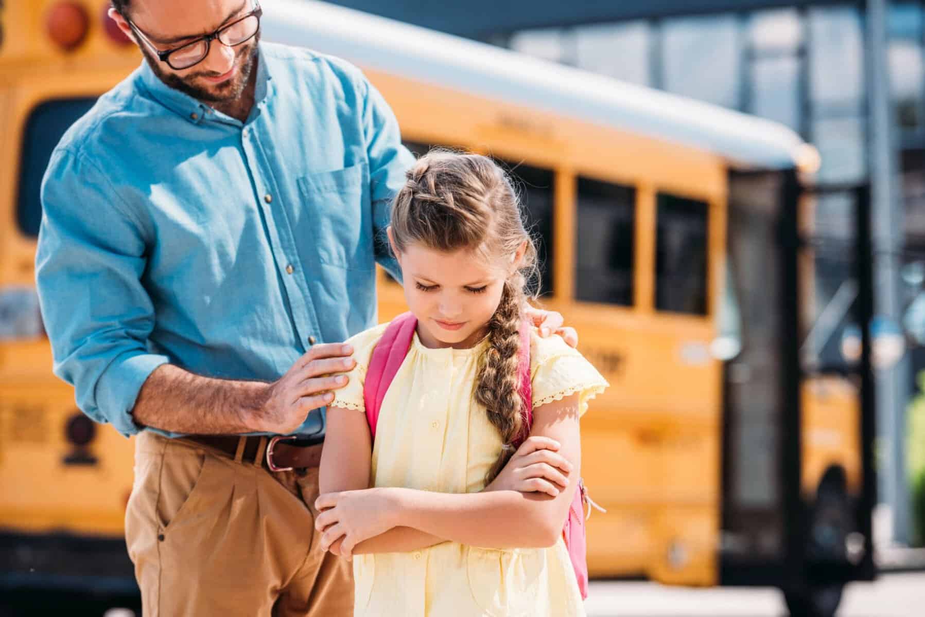 Father encourages crying girl near school bus
