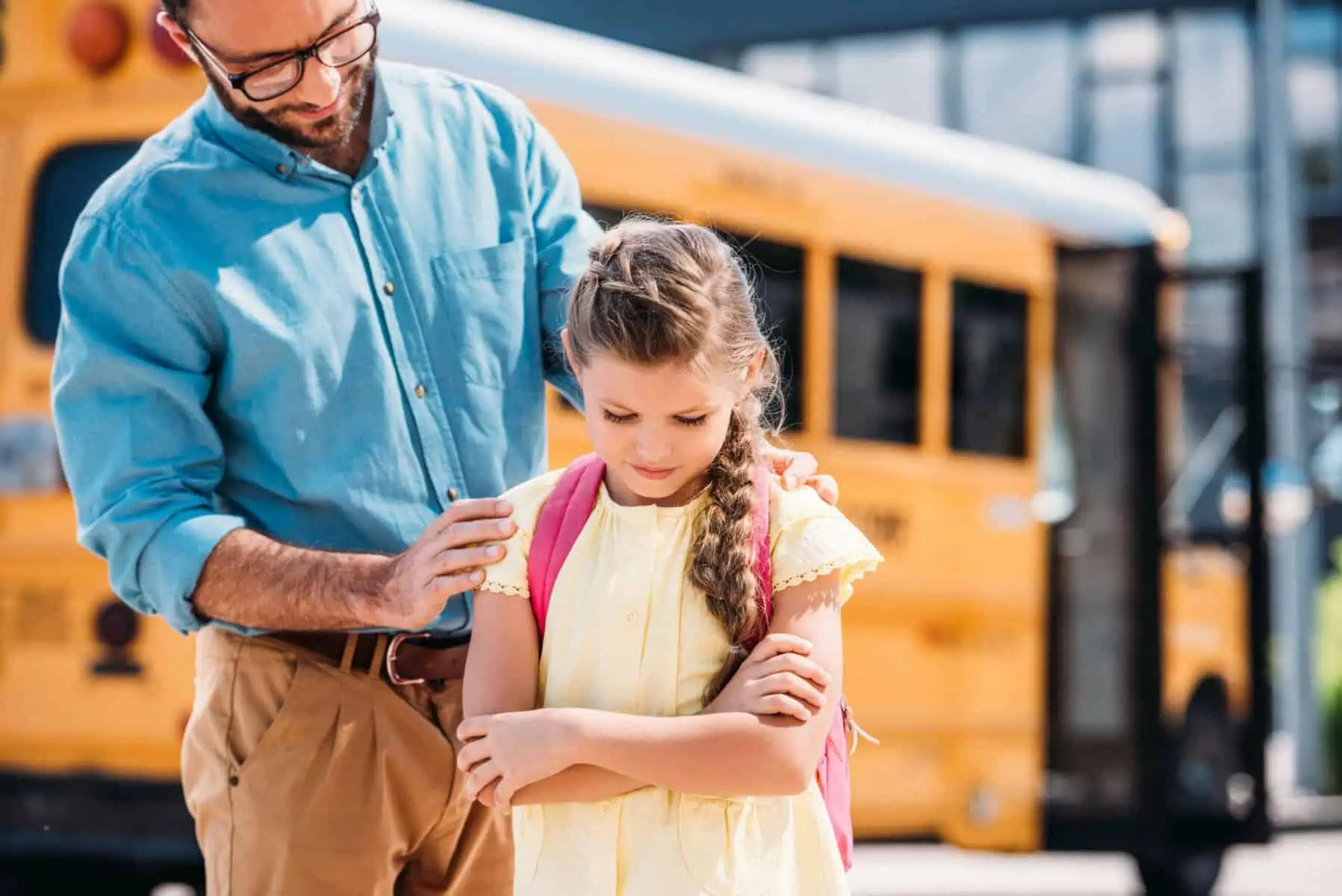 Father encourages crying girl near school bus