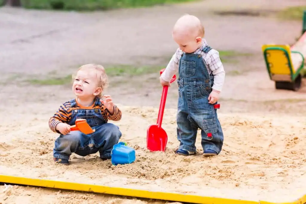Two boys playing with shovels in sand