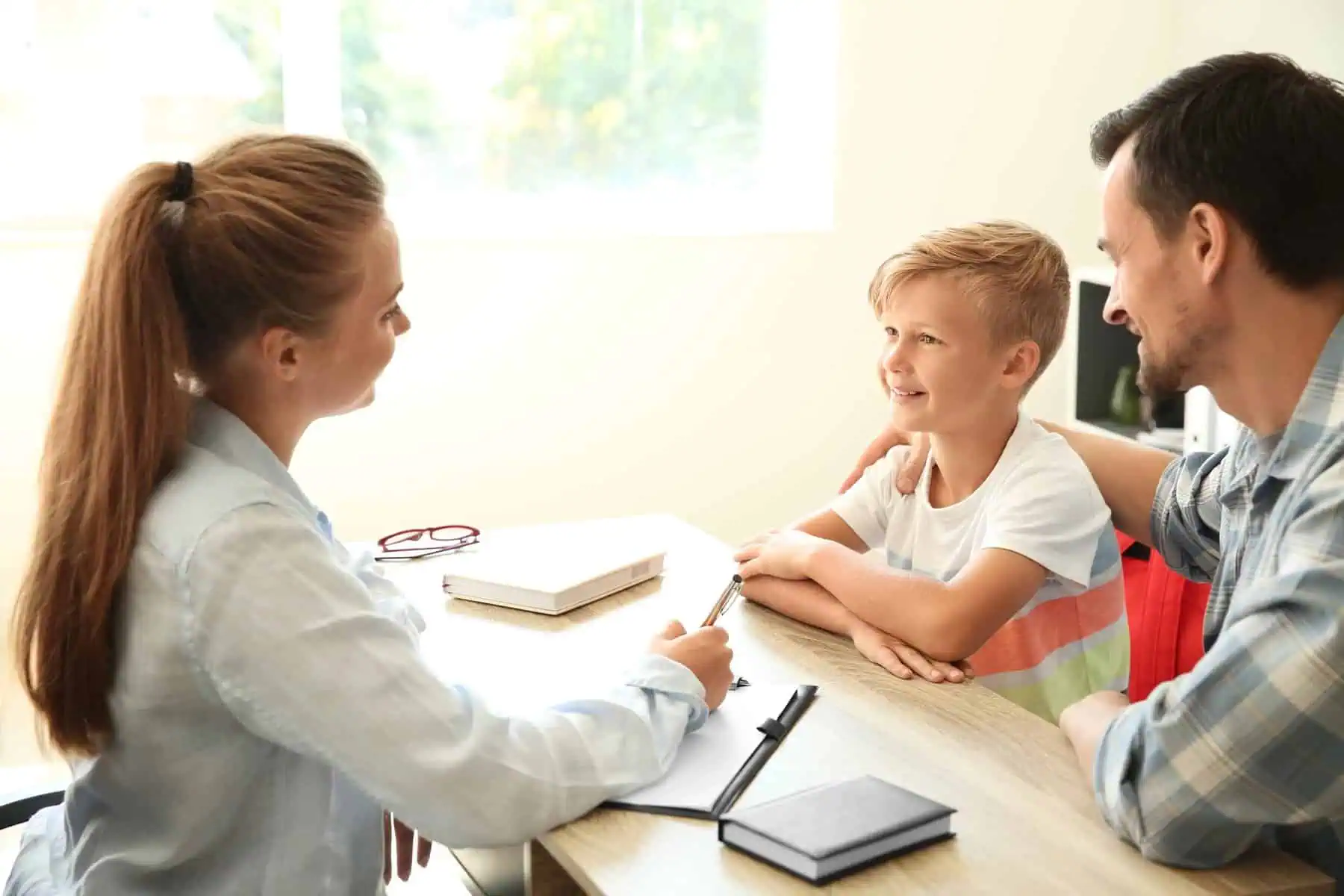 Young man and his son meeting with teacher at school