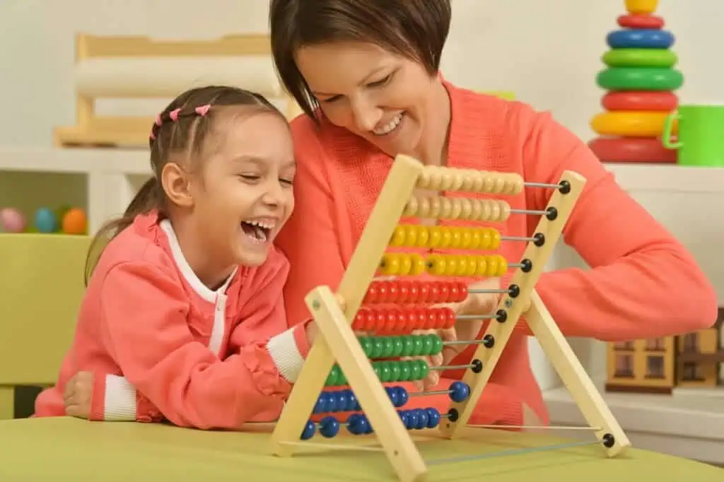 Girl practicing math on abacus with mother