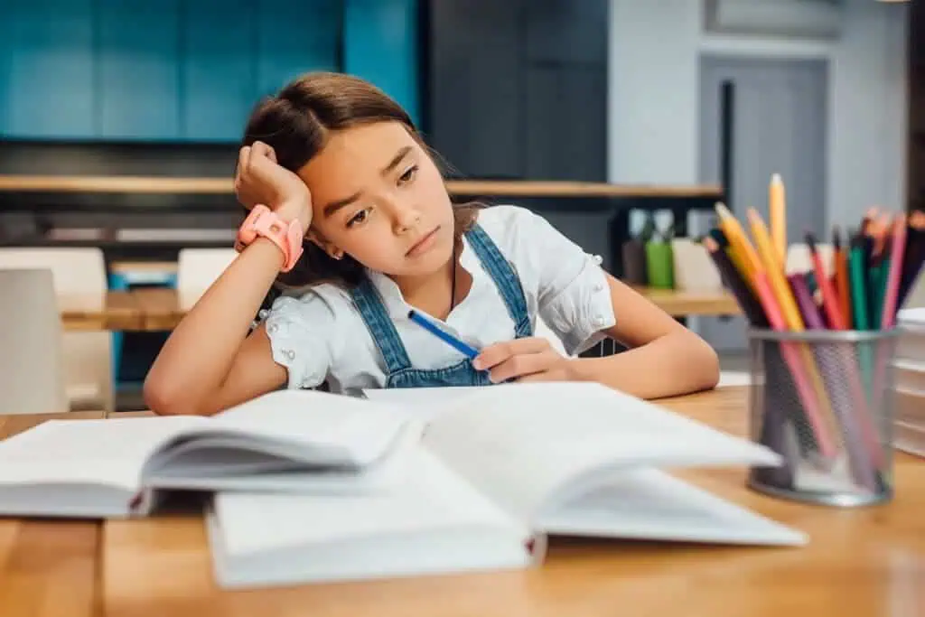 Frustrated girl does homework with several books open
