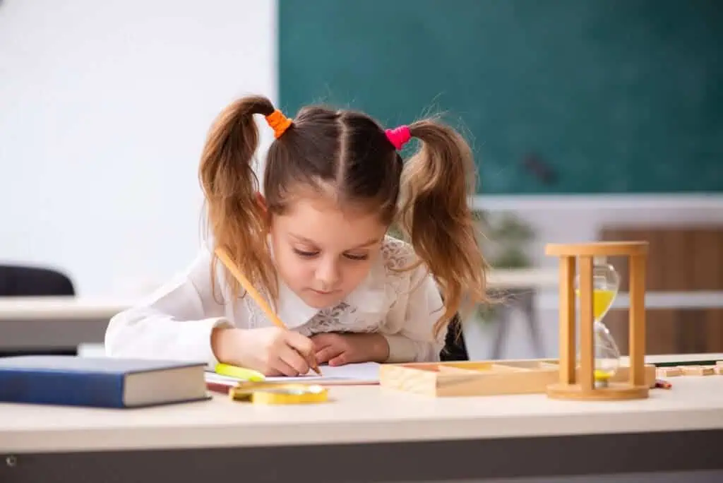 small girl does homework with timer