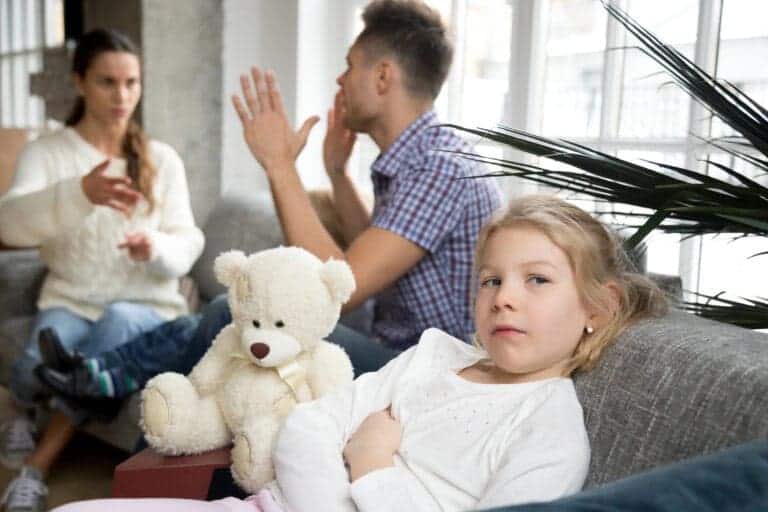 Parents argue in background while daughter looks sad
