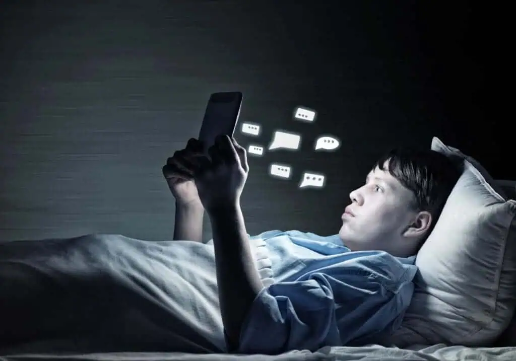 Teenager Reading messages in bed on device