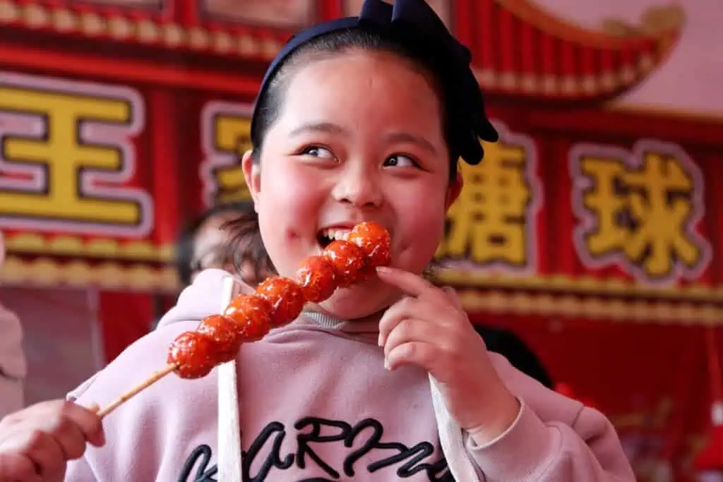 ----A kid enjoys tanghulu, also called bingtanghulu, in Zaozhuang city, east China's Shandong province, 25 March 2018