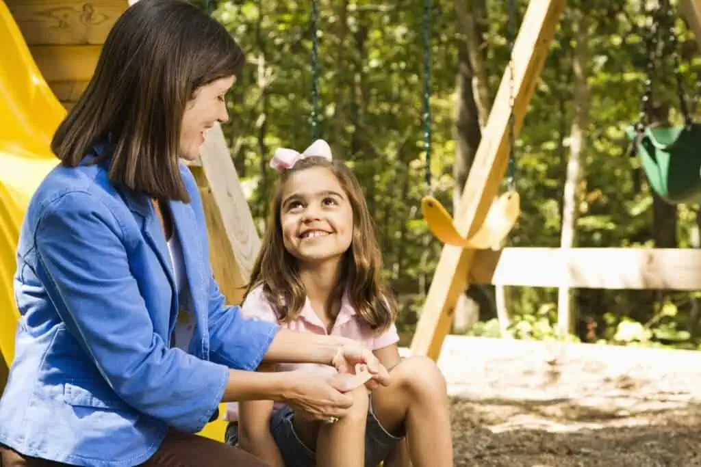 Child looks at mother while having scrape bandaged