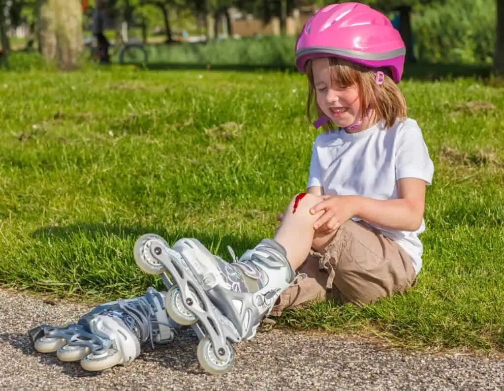 Girl in skates crying with scraped knee