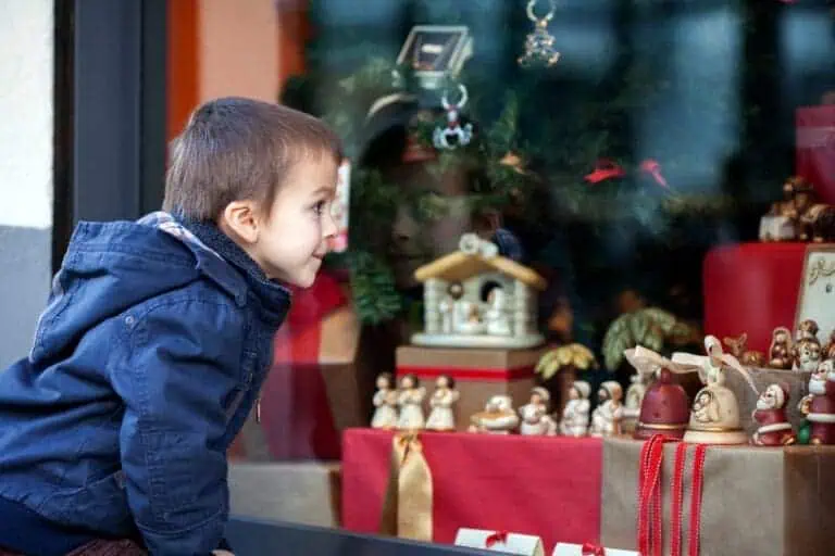 boy excitedly looks into decorated Christmas shop window