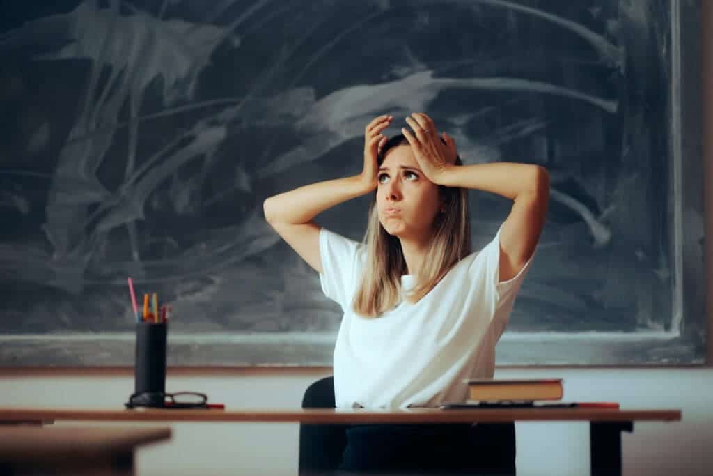 Teacher is overwhelmed and frustrated in front of a blackboard