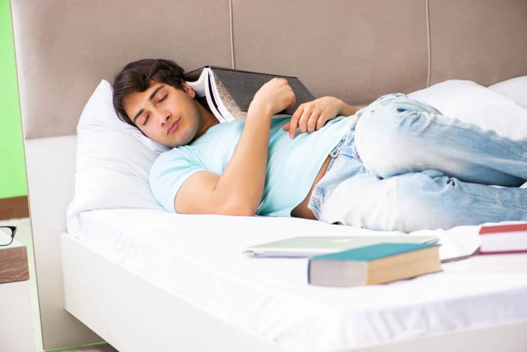 Student is still asleep with books in his bed.