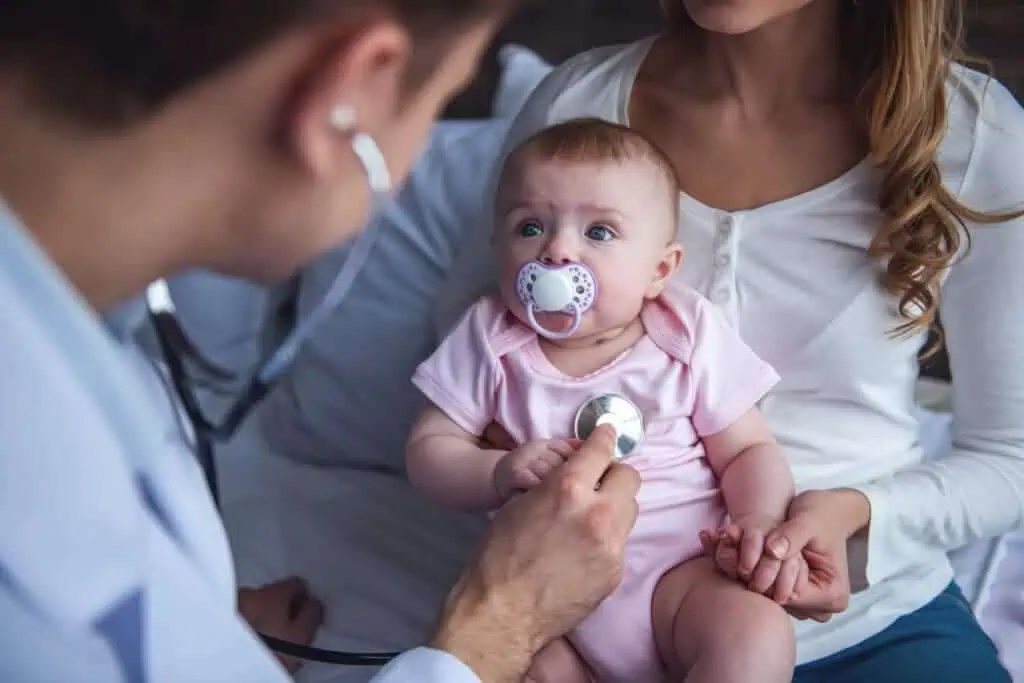 Mom holds baby while pediatrician uses stethoscope