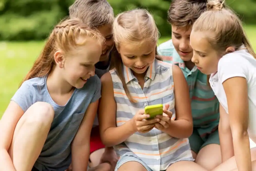 Group of young kids look at cell phone together