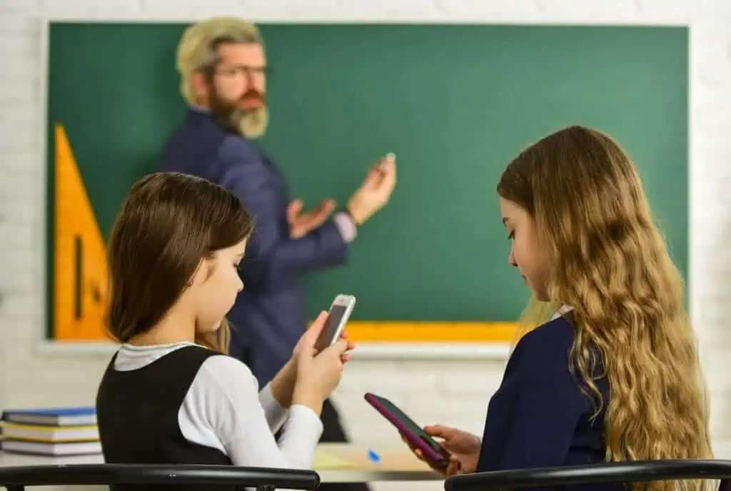 Kids use cell phones in class while ignoring teacher