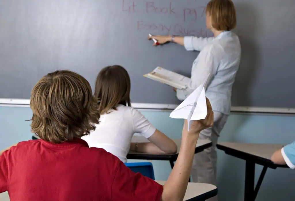 student throws paper plane in classroom