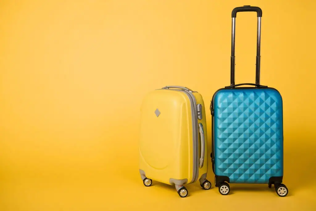 yellow suitcase and blue suitcase in front of yellow background.