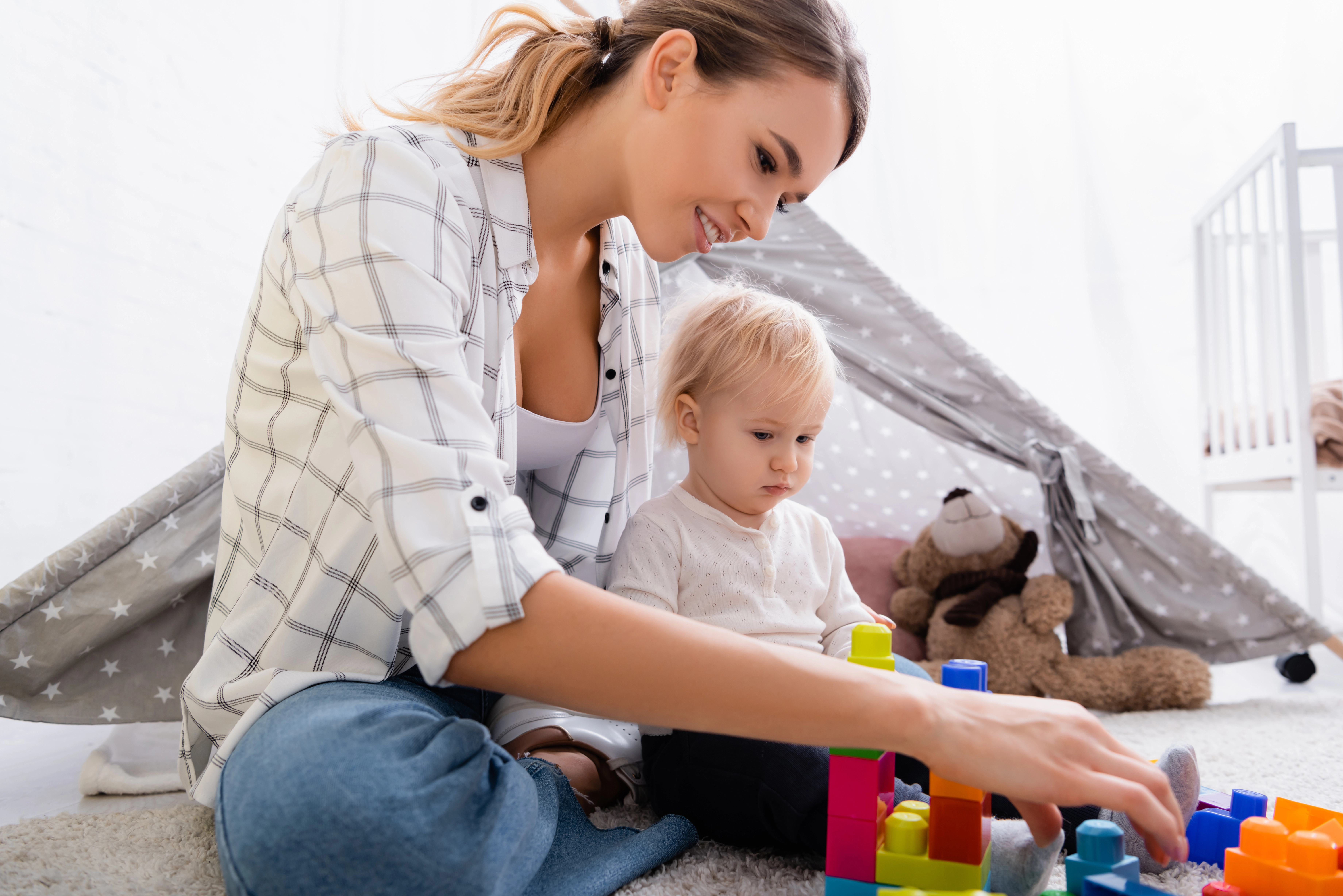 Mom plays with her toddler with toys