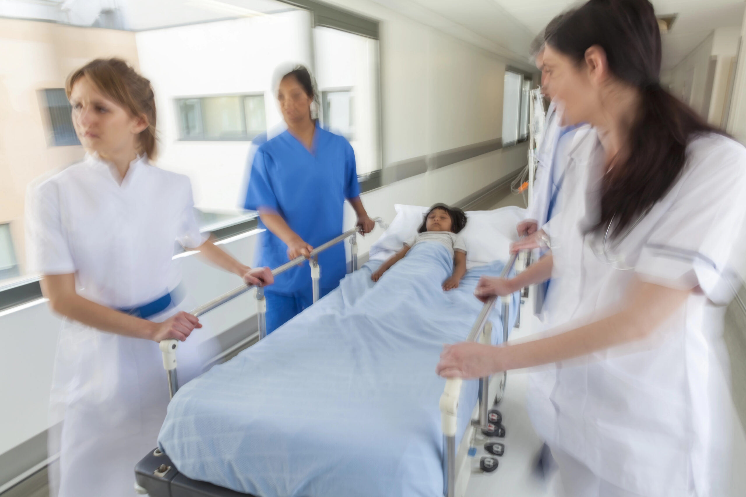Doctors move child on gurney through hospital