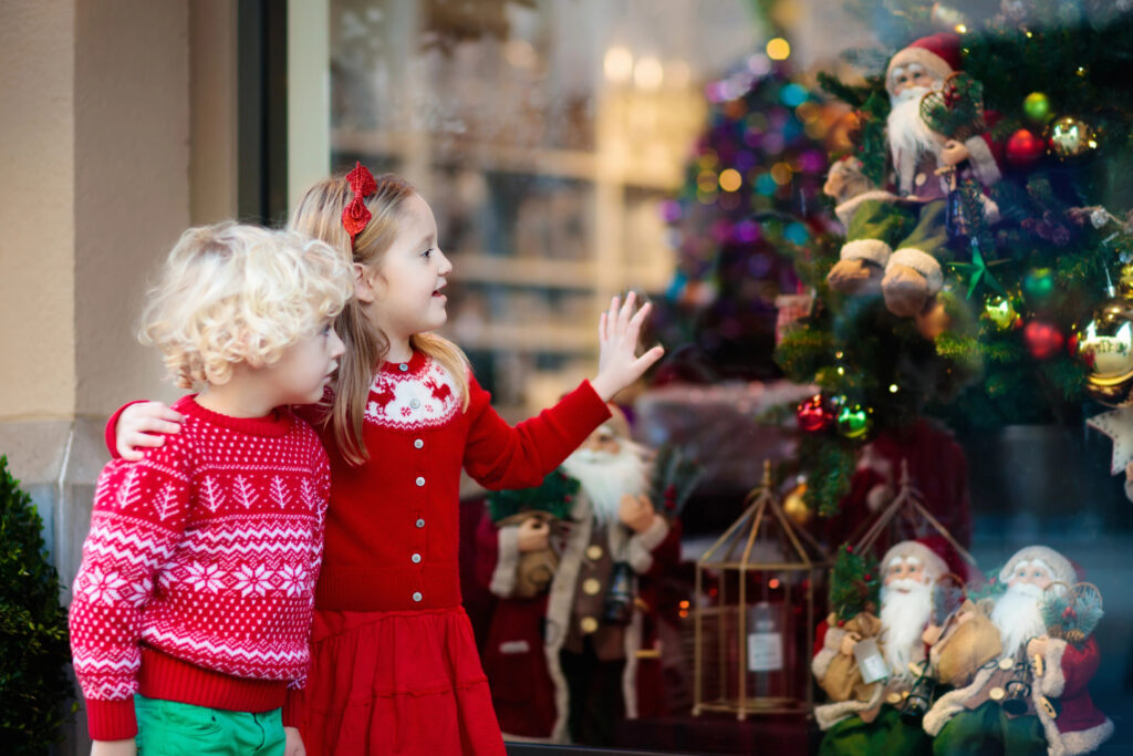 Kids get excited for Christmas outside store window with tree and decorations