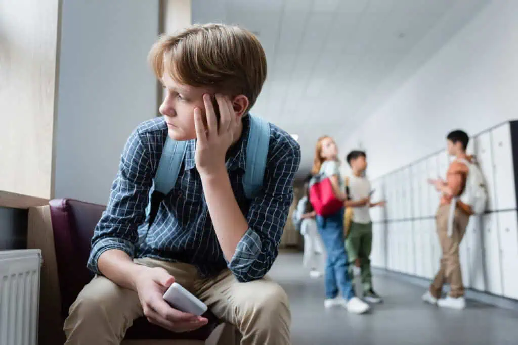 Teen boy sitting alone in school hallway