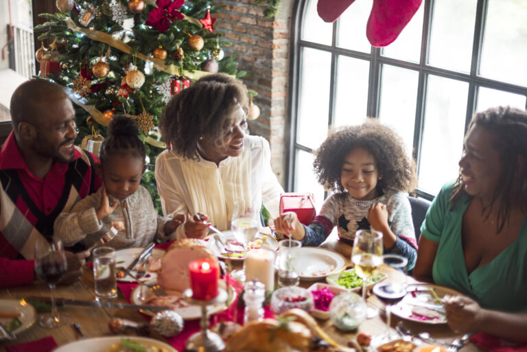 family with kids sitting at table with christmas decorations all around
