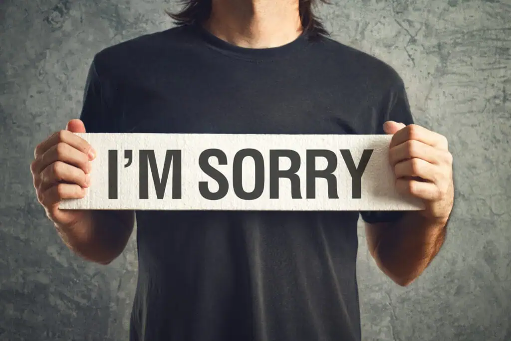 man holding a sign that says 'I'm sorry'
