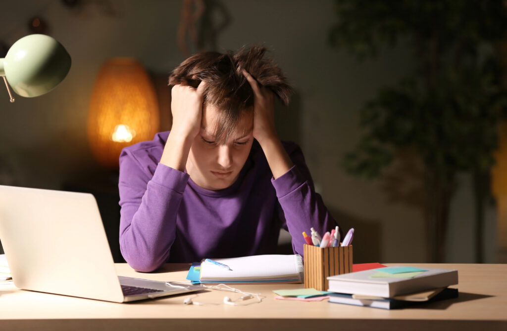 Teenager doing homework at table in evening
