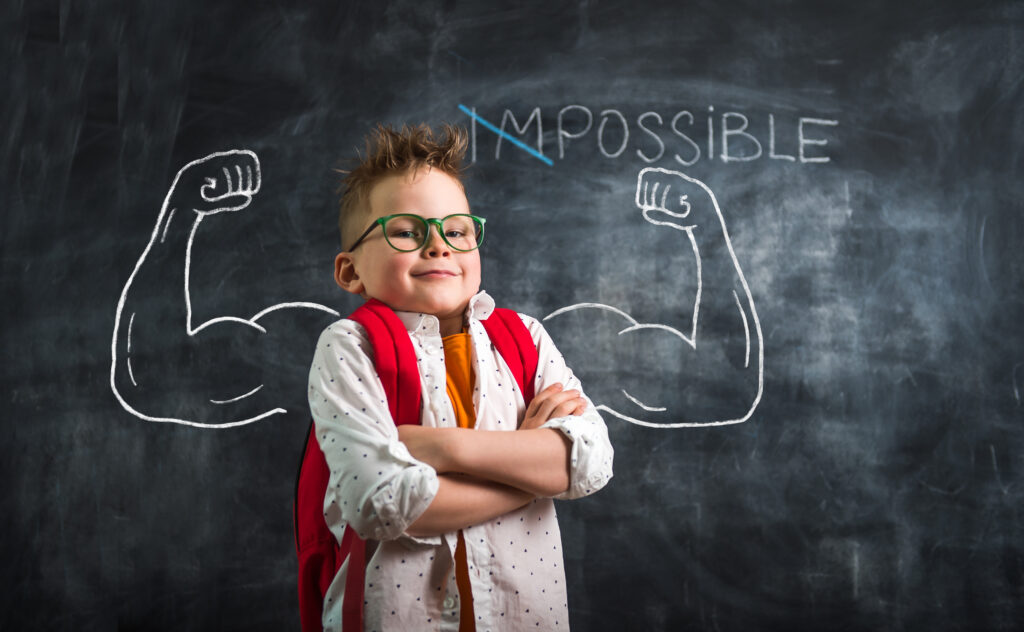 Boy with strong arms against blackboard