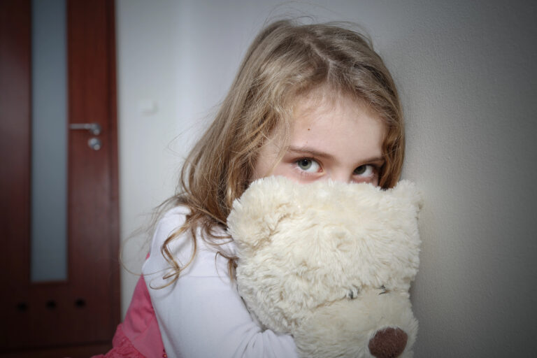 Young sad girl hugging a teddy bear