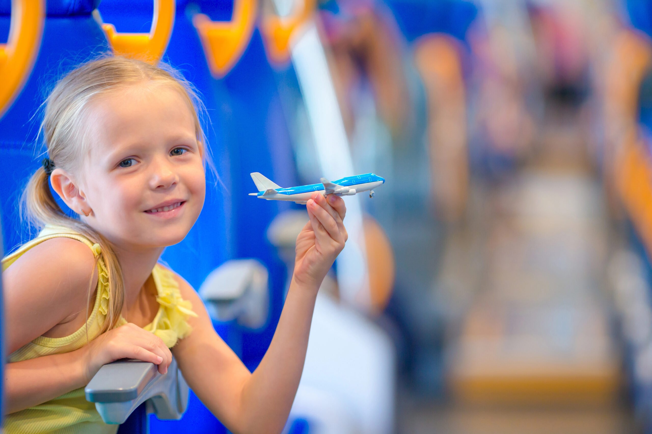 Adorable little girl traveling on train and having fun with airplane model in hands