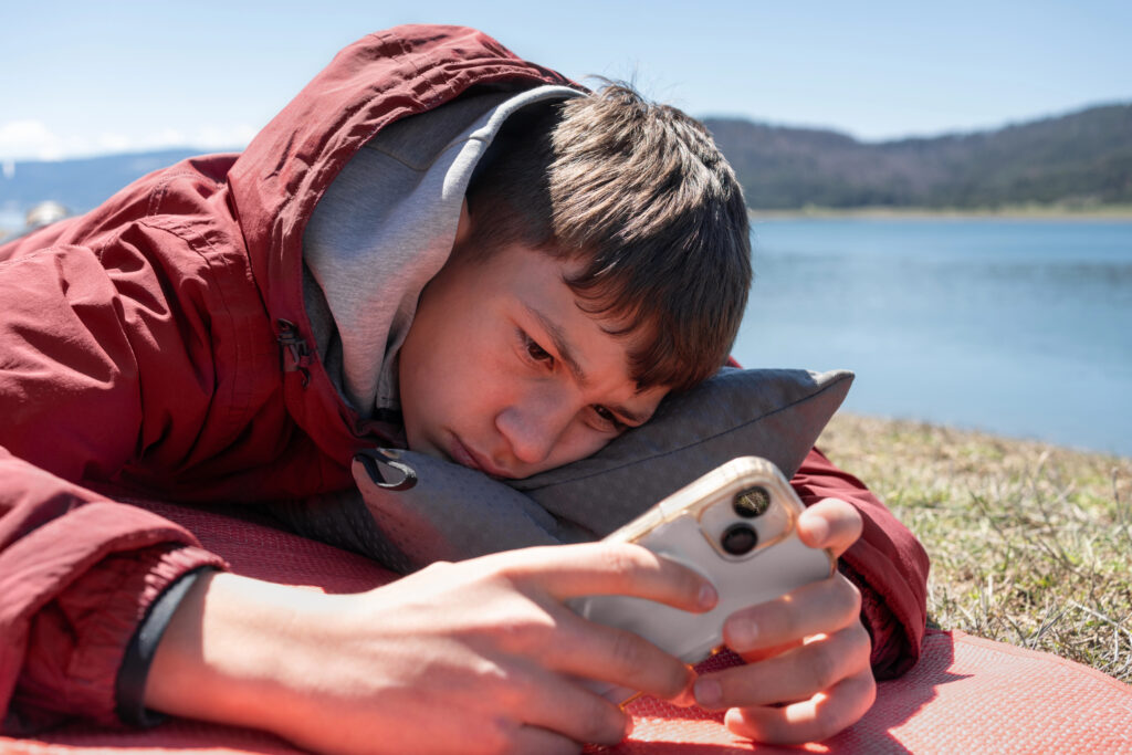 teenager in a coat ignoring the world while he scrolls on a cellular mobile device