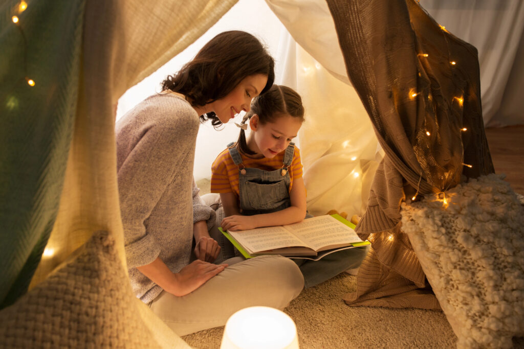 happy family reading book in kids tent at home