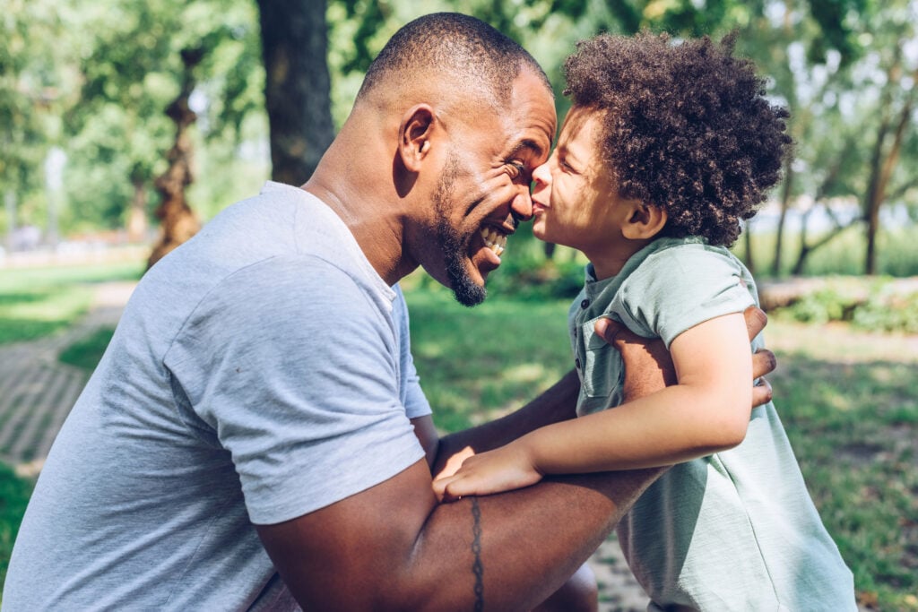 A dad is hugging his child and caring for him in a park