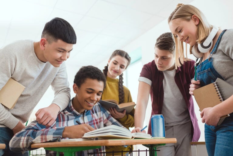 Students lean together while sharing a project
