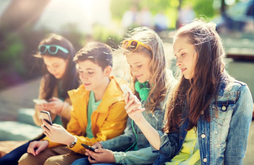 happy teenage friends with smartphones outdoors