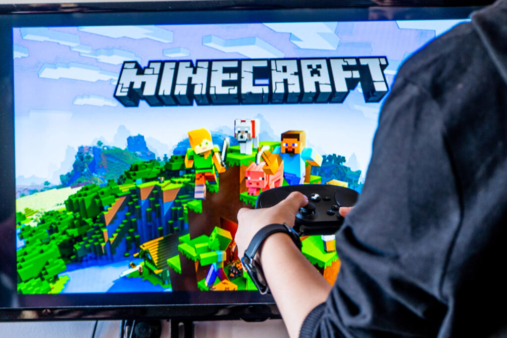 Woman holding a steam controller and playing popular video game minecraft on a television and PC