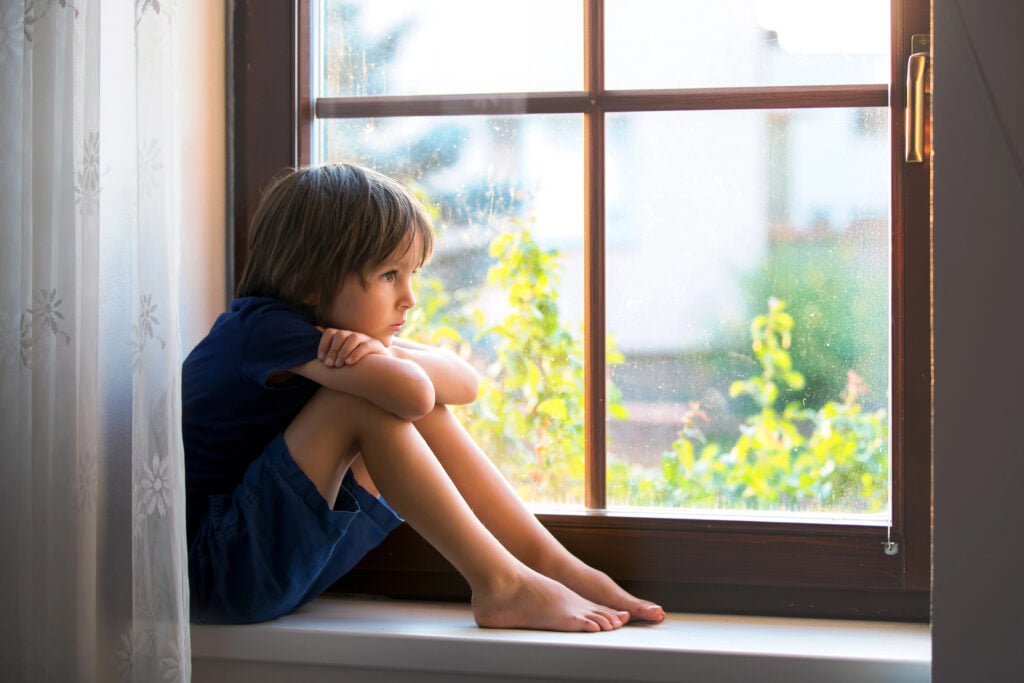 A child sits in the window, bored
