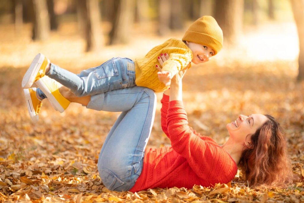 Mom enjoying autumn leaves with baby