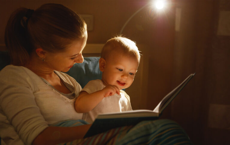 mother reads to baby book in bed