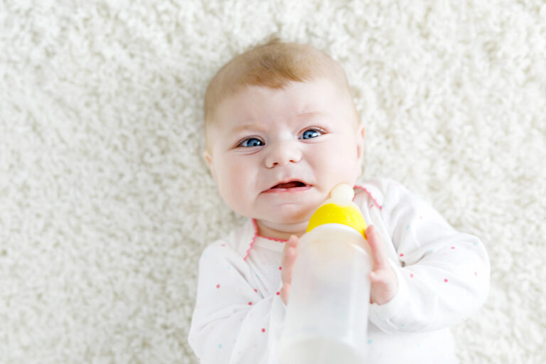 Baby frowns with bottle of formula