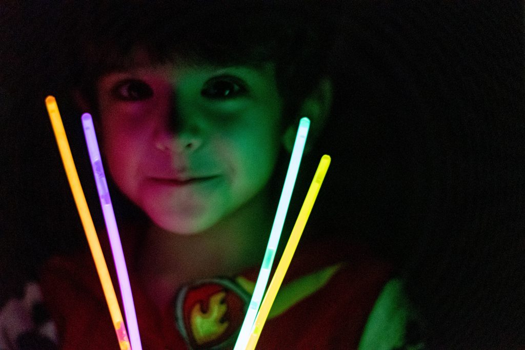 A boy playing with glow sticks in lowlight conditions