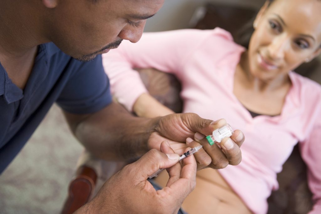 Man helping woman inject drugs to achieve pregnancy at home
