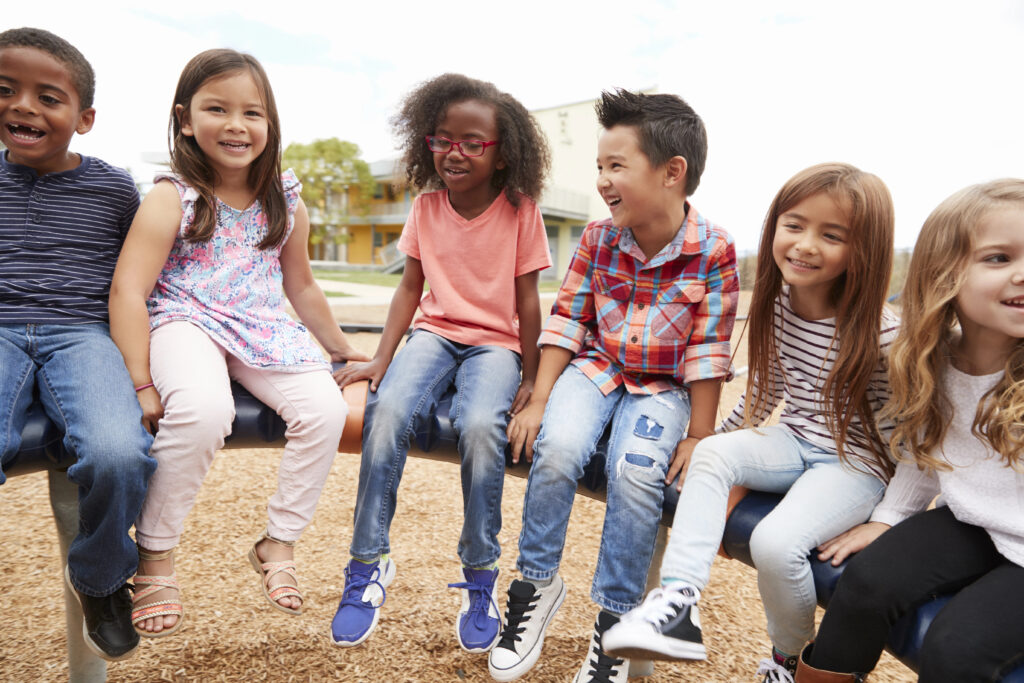 Elementary school friends sitting on spinning carousel