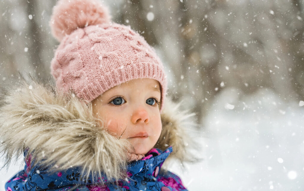 toddler girl is wearing heavy coat and hat in snow
