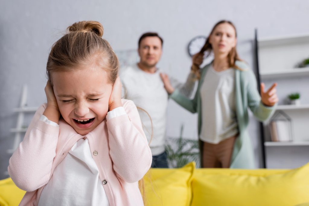 Scared child screaming while parents quarrelling at home