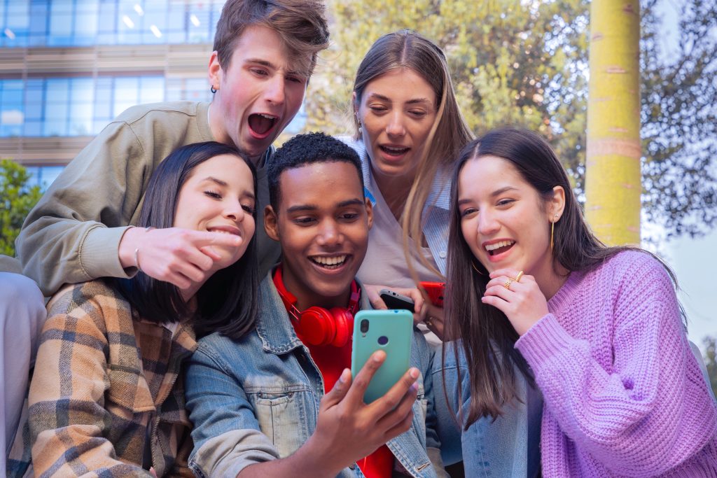 Group of friends using looking at their smartphones Multiracial teenagers browsing the internet with mobile phone on campus