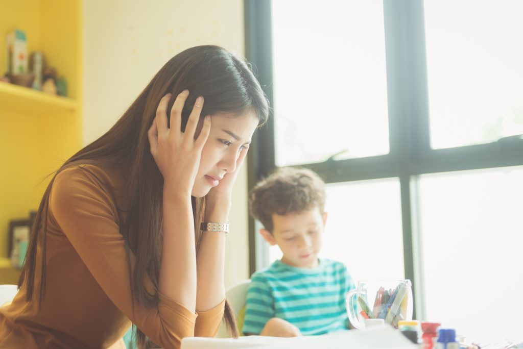 Stressed teacher with homeschooled student in the background.