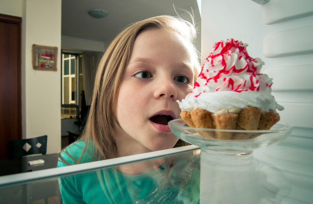 girl sees the sweet cake in the fridge