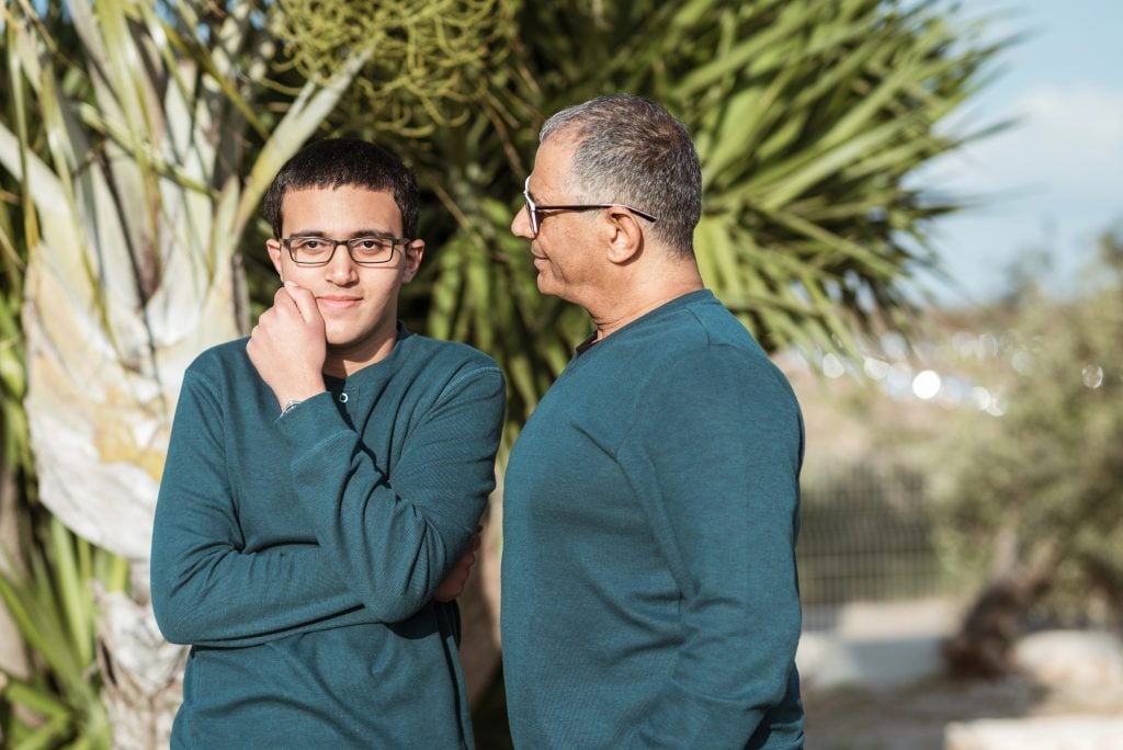Teenager boy with father walking in park.